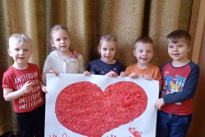 piątka dzieci trzyma plakat z dużym czerwonym sercem