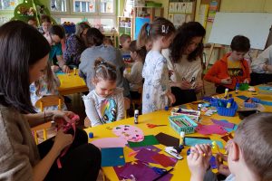 Rodzice i dzieci w przedszkolu tworzą papierowe pisanki