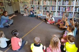 dzieci siedzą w kręgu w bibliotece