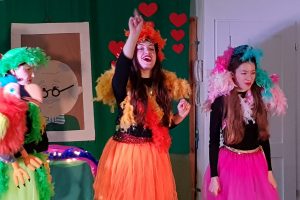 scena z teatrzyku - Trzy kolorowo ubrane tancerki i ptak kukiełka