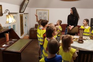 przedszkolaki w muzeum oglądają stary pokój mieszkania w powojennym Wrocławiu