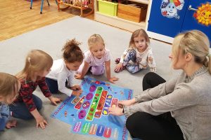 dzieci siedzą na dywanie i oglądają piramidę żywien