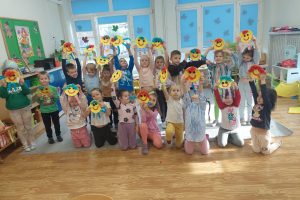 zdjęcie grupy dzieci trzymających uśmiechnięte buźki wykonane z talerzyków