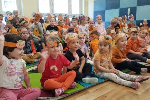 Dzieci z opaskami z dynią radosne siedzą na sali przedszkolnej